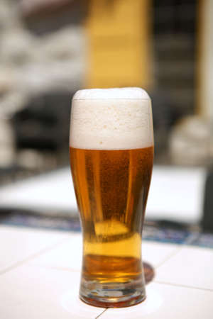single full beer glass with bubbles on table