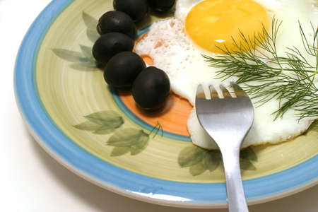 fried egg with tomato and olives on dishの写真素材