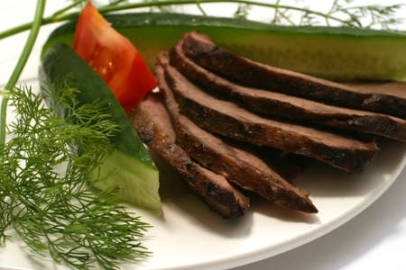 sliced beef and green vegetables on white dishの写真素材