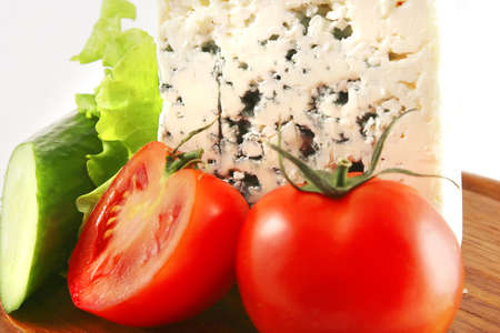 blue cheese and vegetables on cut wooden plateの写真素材
