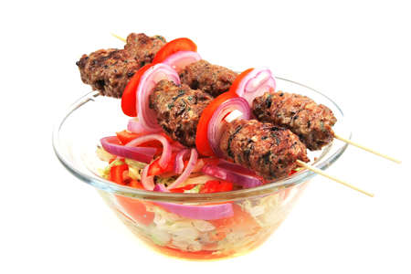 greek kebab on skewer over salad bowlの写真素材