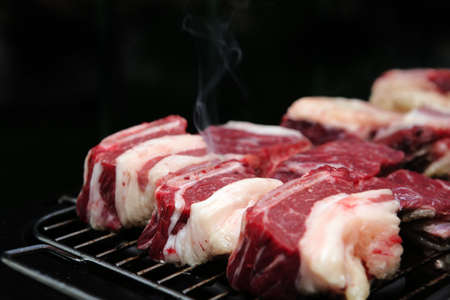 fresh red uncooked cuts of meat on bbqの写真素材