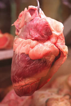 bloody heart hanging on hook on show windowの写真素材