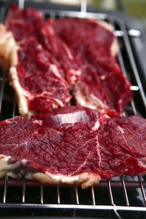 uncooked fresh red juicy meat close up on bbqの写真素材