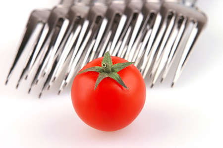 forks and tomato isolated over white backgroundの写真素材