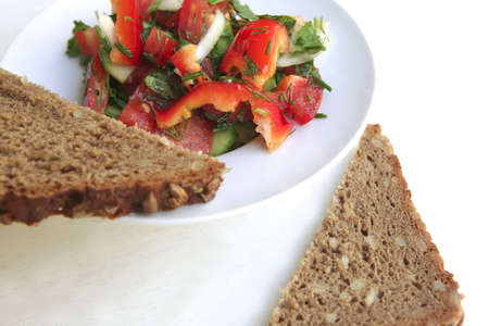 tomato salad and rye bread on white tableの写真素材
