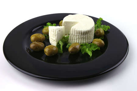 soft feta cheese on black dish with gold olivesの写真素材