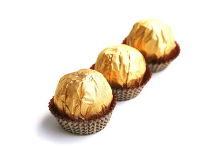 candy in golden foil over white background
