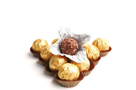 candy in golden foil over white background