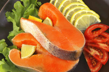 two salmon steak on dark dish over whiteの写真素材