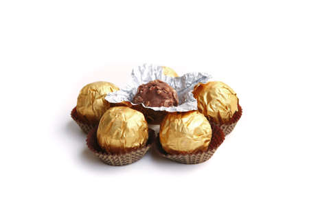 candy in golden foil over white backgroundの写真素材