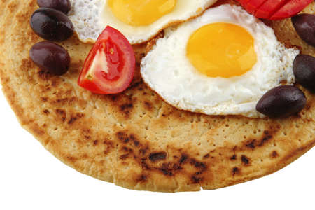 fried eggs on pancake over white with vegetables