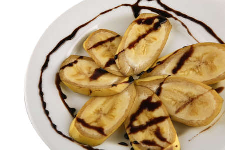 banana with chocolate sauce served on whiteの写真素材