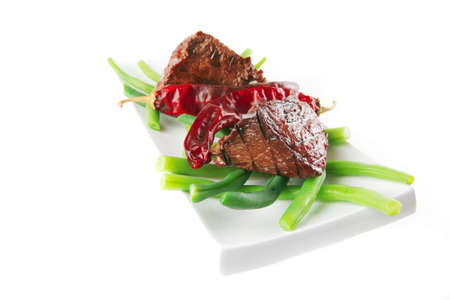 served roast veal fillet on a white plate with peppersの写真素材