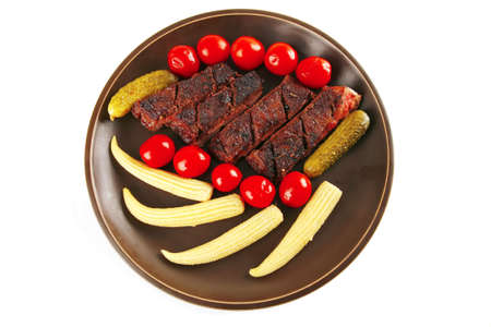 meat served with baby corns on dark plateの写真素材