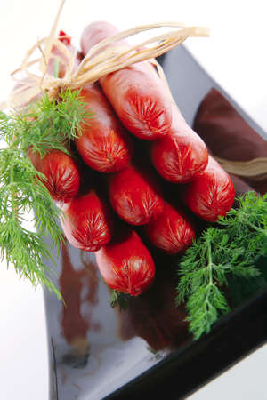 smoked sausages on a black plate over whiteの写真素材