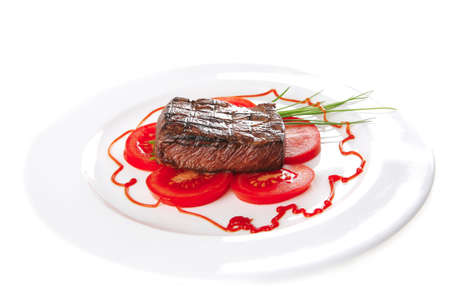 served roasted beef meat with tomato on white dishの写真素材