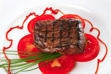 served roasted beef meat with tomato on white dishの写真素材