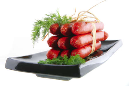 smoked sausages served on a black plate over whiteの写真素材