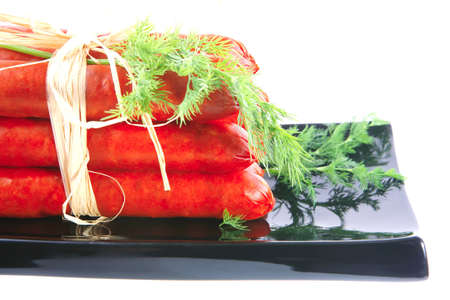 smoked sausages served on a black plate over whiteの写真素材