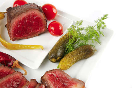 meat with tomato and cucumbers on white platesの写真素材