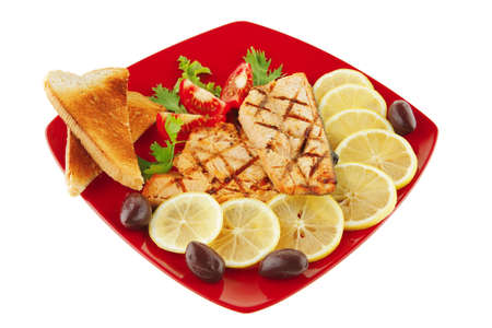 grilled salmon steak on red plate with tomatoesの写真素材