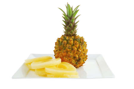 fresh pineapple and slices on white dishの写真素材