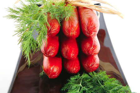smoked sausages served on a black plate over whiteの写真素材