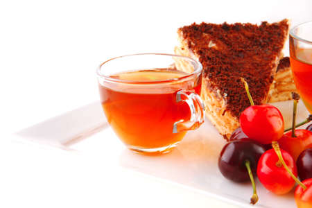 tea and cherry with cakes on white plateの写真素材