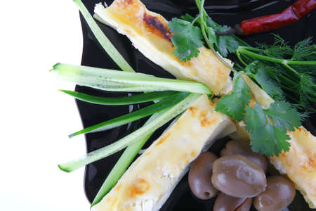 cheese cannelloni served with pepper and olives on black plateの写真素材