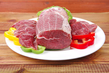 raw meat on plate over wooden table