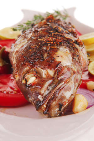 whole fried bass on plate, served with lemons and tomatoes
