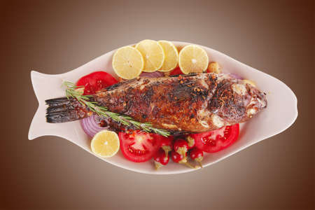 served main course: whole fried seabass served on plate with lemons,tomatoes and peppers