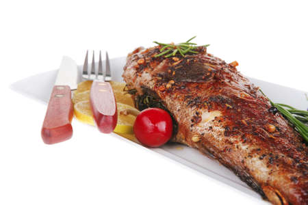 whole fried bass on plate, served with lemons and tomatoes isolated on white