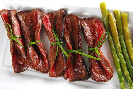 roast beef slices on white plate with asparagusの写真素材