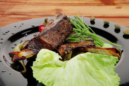 sawory on black: grilled ribs on plate over wooden tableの写真素材