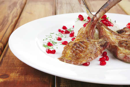 main course: grilled ribs with rice and tomatoes on white dish over woodの写真素材