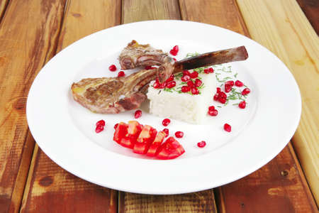 meat savory: roast veal ribs with rice garnish and pomegranate seeds on white over woodの写真素材