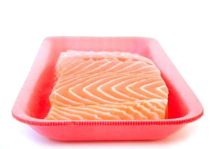 piece of fresh raw salmon on red tray isolated on white backgroundの写真素材