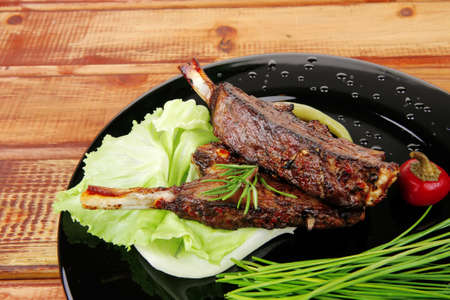 sawory on black: grilled ribs on plate over wooden table . shallow dofの写真素材