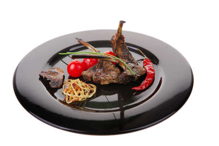 grilled ribs on black plate with vegetablesの写真素材