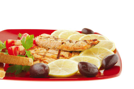 grilled salmon steak on red plate with tomatoesの写真素材