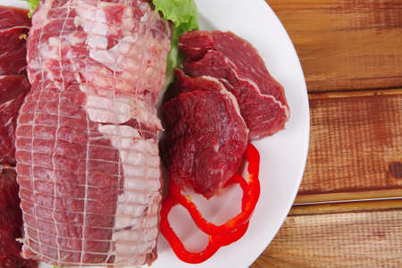 fresh red meat with vegetables on wood
