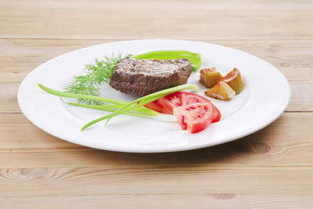 meat savory : grilled beef fillet mignon served on white plate over wooden table with chili pepper and tomatoesの写真素材