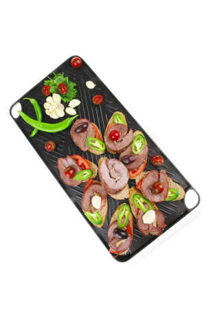 snakes on black grill plate : tartlets with sliced meat isolated over white background