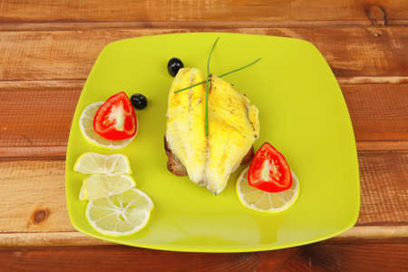 served roast golden fish fillet over wooden table with tomatoes and olives の写真素材