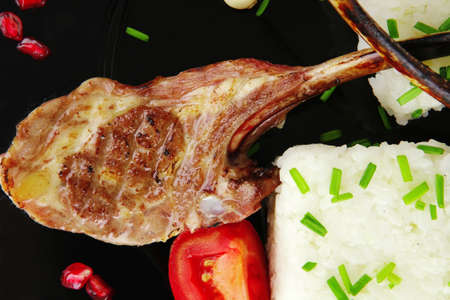 meat food: ribs on black with rice garnich and tomatoes on black over white backgroundの写真素材