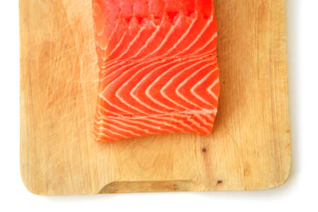fresh raw salmon fish piece over wooden board isolated on white background
