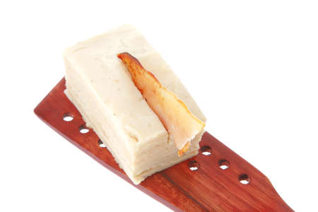 small cream cake on wooden spatula over white