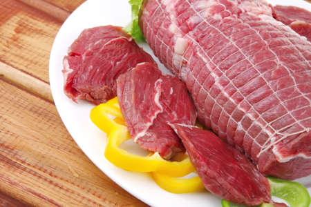 raw uncooked meat on wooden table with vegetables